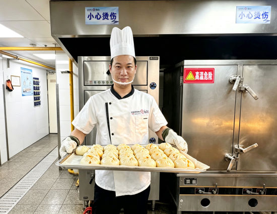 “华东印记”上海兴铁餐厅面点师端着刚出蒸箱的包子。王丹 摄 “华东印记”上海兴铁餐厅面点师端着刚出蒸箱的包子。王丹 摄