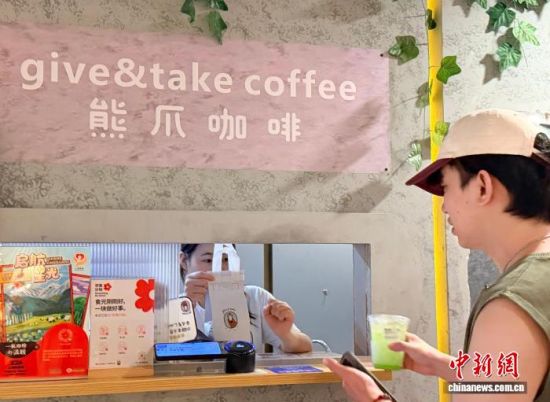 8月31日,地处上海市中心淮海中路的一家熊爪咖啡门店里,一名工作人员从窗口给顾客递出饮品。中新社记者 郑莹莹 摄 8月31日,地处上海市中心淮海中路的一家熊爪咖啡门店里,一名工作人员从窗口给顾客递出饮品。中新社记者 郑莹莹 摄