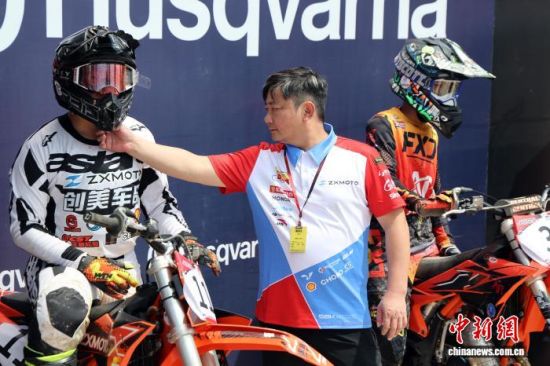 9月12日,2026世界摩托车越野锦标赛(MXGP)中国上海站在海湾户外运动场举行。“张雪机车”创始人张雪现身赛场,为参加85CC组赛事的儿子张擎天助阵。图为张雪(中)赛前为儿子调试头盔护具。 中新社记者 汤彦俊 摄 9月12日,2026世界摩托车越野锦标赛(MXGP)中国上海站在海湾户外运动场举行。“张雪机车”创始人张雪现身赛场,为参加85CC组赛事的儿子张擎天助阵。图为张雪(中)赛前为儿子调试头盔护具。 中新社记者 汤彦俊 摄