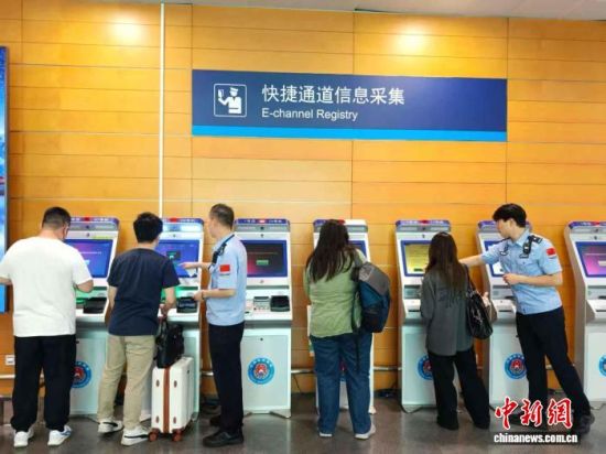 移民管理警察协助港澳台旅客完成快捷通道信息采集。(王熙熙摄) 移民管理警察协助港澳台旅客完成快捷通道信息采集。(王熙熙摄)